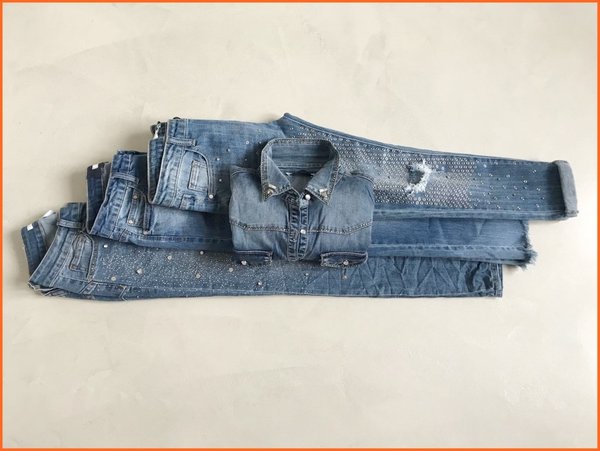 Jeans delavè con rotture e borchiette.