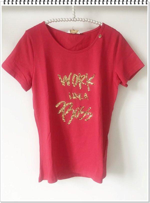 T-shirt corallo con scritta dorata in paillettes.