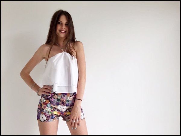 Crop top bianco su short in fantasia con pietre colorate applicate.