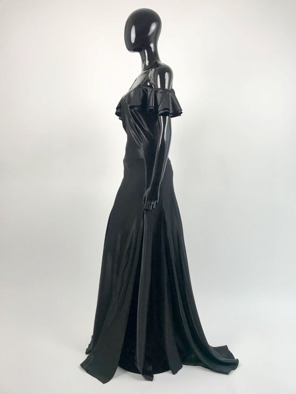Gil Santucci propone abito lungo svasato di raso nero con rouches al decolletè.