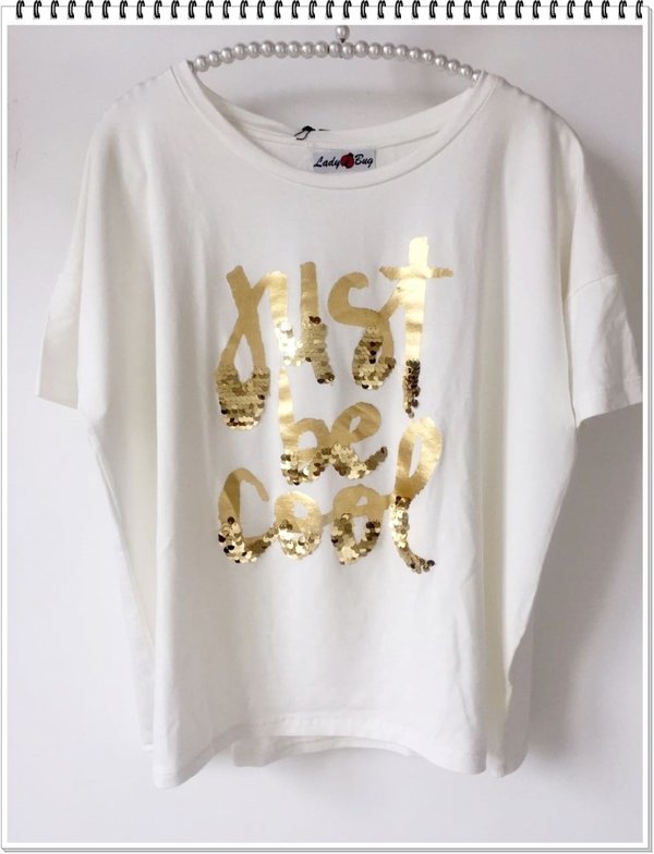 Over t-shirt bianco burro con scritte dorate.