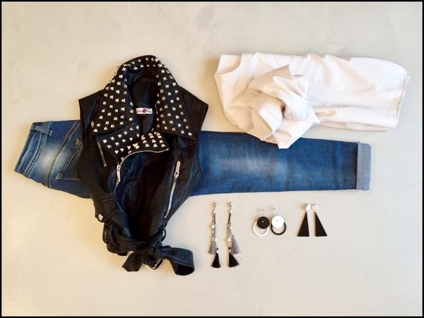 Gilet nero borchie argentate, jeans risvolto, giubbetto ecopelle bianco e orecchini bicolore anni '70.