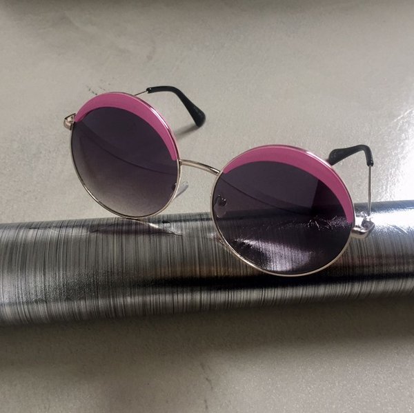 Round glasses con lente scura e finitura fucsia.