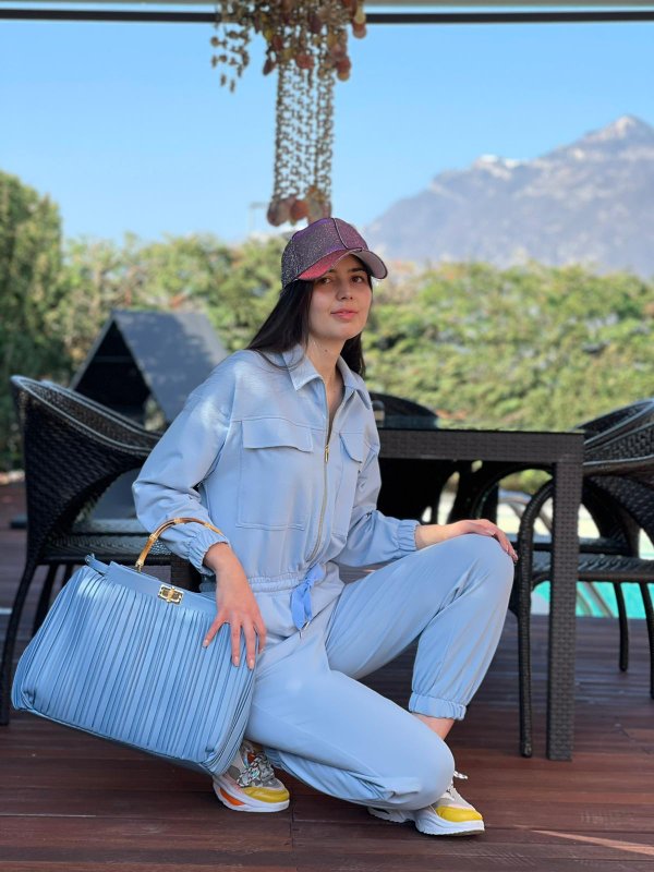 Jumpsuit in felpa azzurra, borsa e cappellino luminoso.