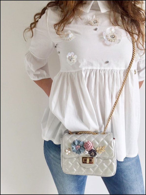 Camicia con fiori applicati, mini bag tracolla con fiori colorati e jeans corto.