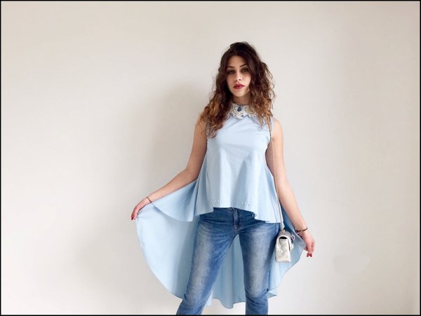 Camicia svasata azzurra con collettino in pizzo e perle su jeans.