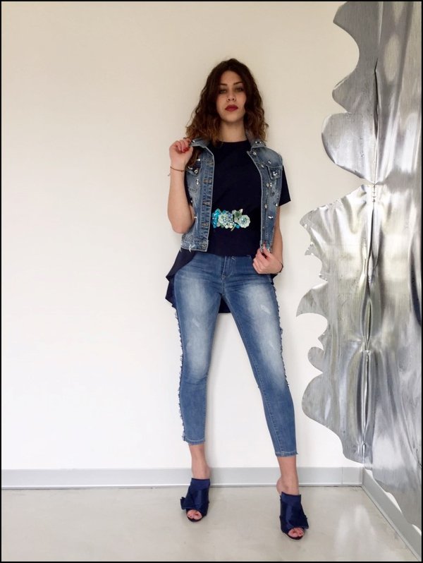 Jeans con bande in tulle blu con casacca svasata e cintura applicazioni fiori e gilet jeans con pietre. Sabot in raso blu.