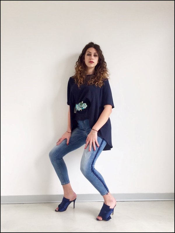 Jeans con bande laterali in tulle blu e casacca svasata con cintura fiori applicati.