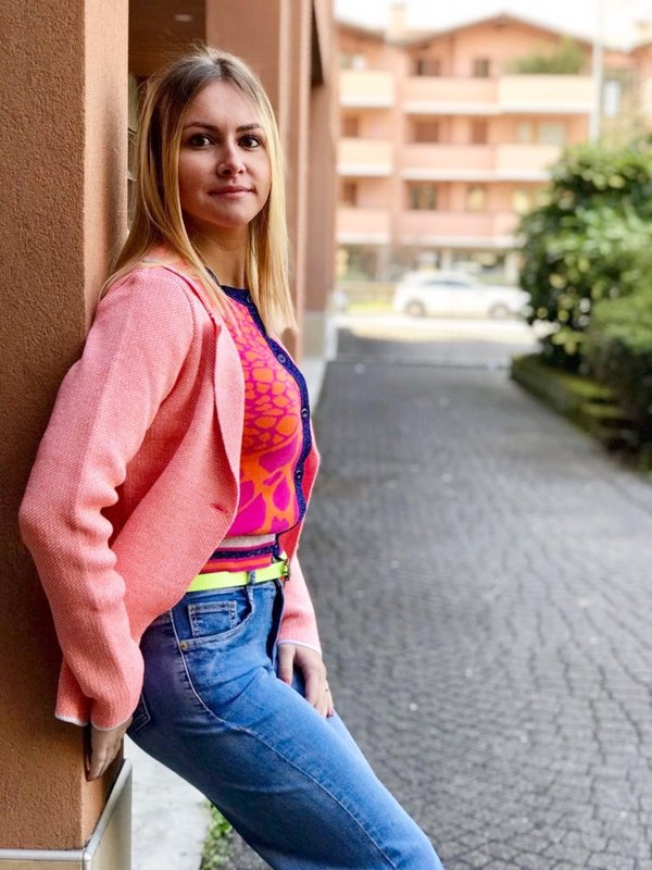 Giacca lurex rossa con cardigan corto fluo e jeans.