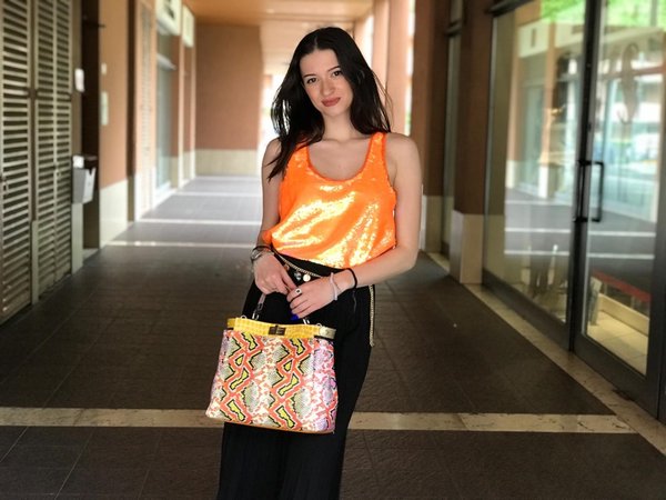 Top paillettes arancio con pantagonna plissè nera e borsa patchwork piton print.