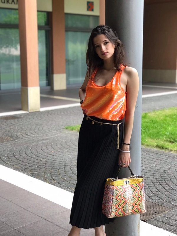 Borsa patchwork piton print, pantagonna plissè nera e top paillettes arancio.