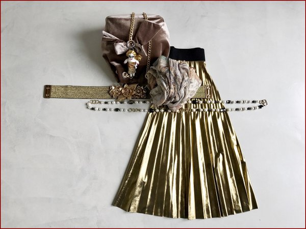 Gonna plissè dorata, collana lunga perle, pashmina colorata in lurex, cintura elasticizzata con fiori applicati, borsa in velluto e charms bambolina.