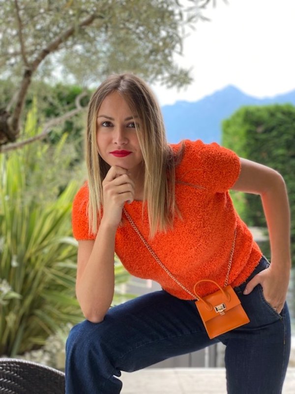 Maglia e minibag arancio fluo e jeans.